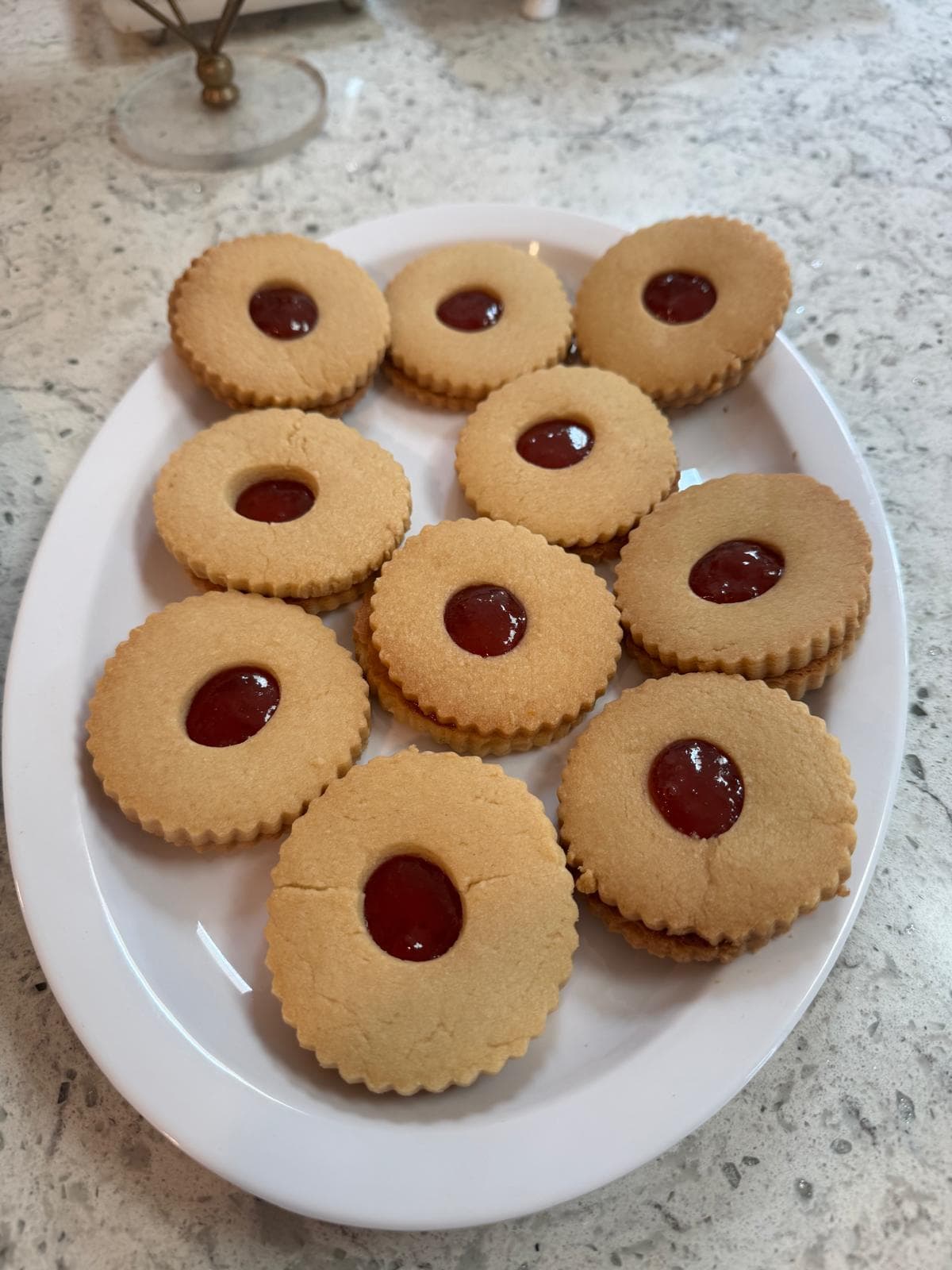 Shortbread cookies with red jam centers on a white plate