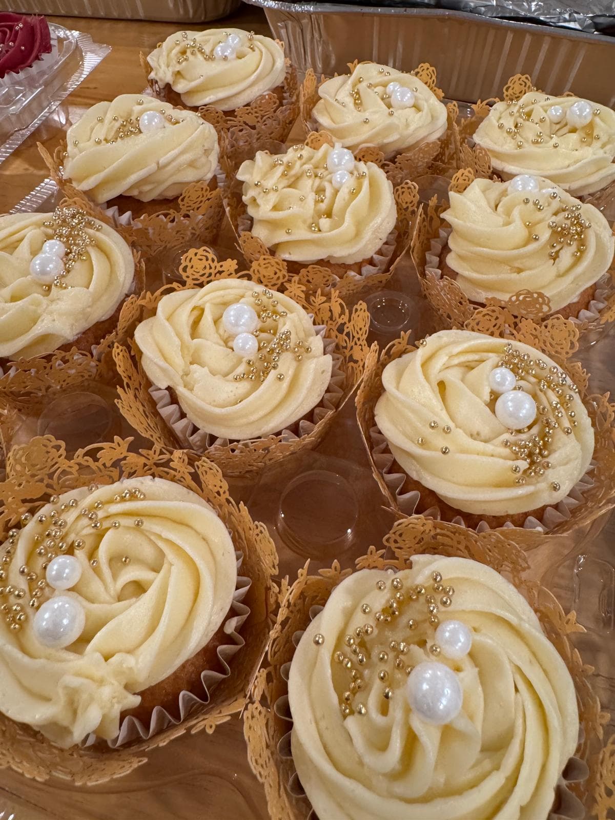 Ivory rose-piped cupcakes with gold pearls in gold lace wrappers